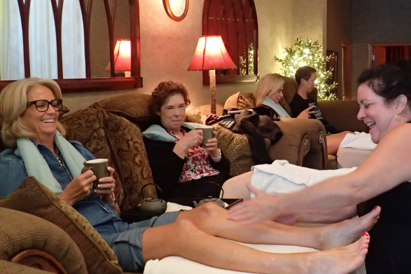 Group massage party at Footloose Massage Center with a party of four happily being massaged by smiling therapist