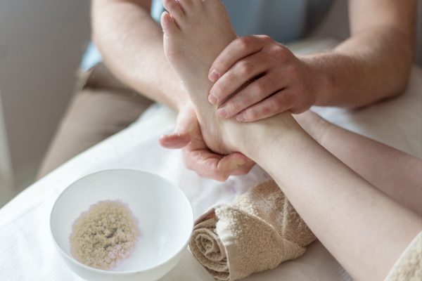 Therapist hands massaging client feet using "Salt Glow" treatment of feet